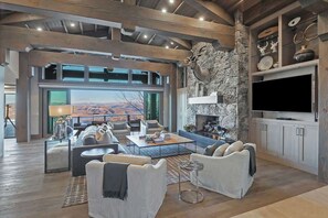 A spacious living room with a stone fireplace, modern furniture, and a large TV.