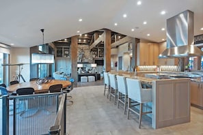 A modern kitchen with a central island, bar stools, and a dining area with a round table and chairs.