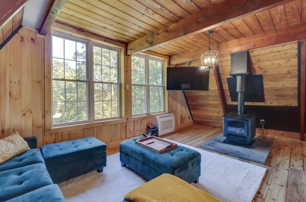 Una cabaña de madera acogedora con un ventanal grande, chimenea y televisor.