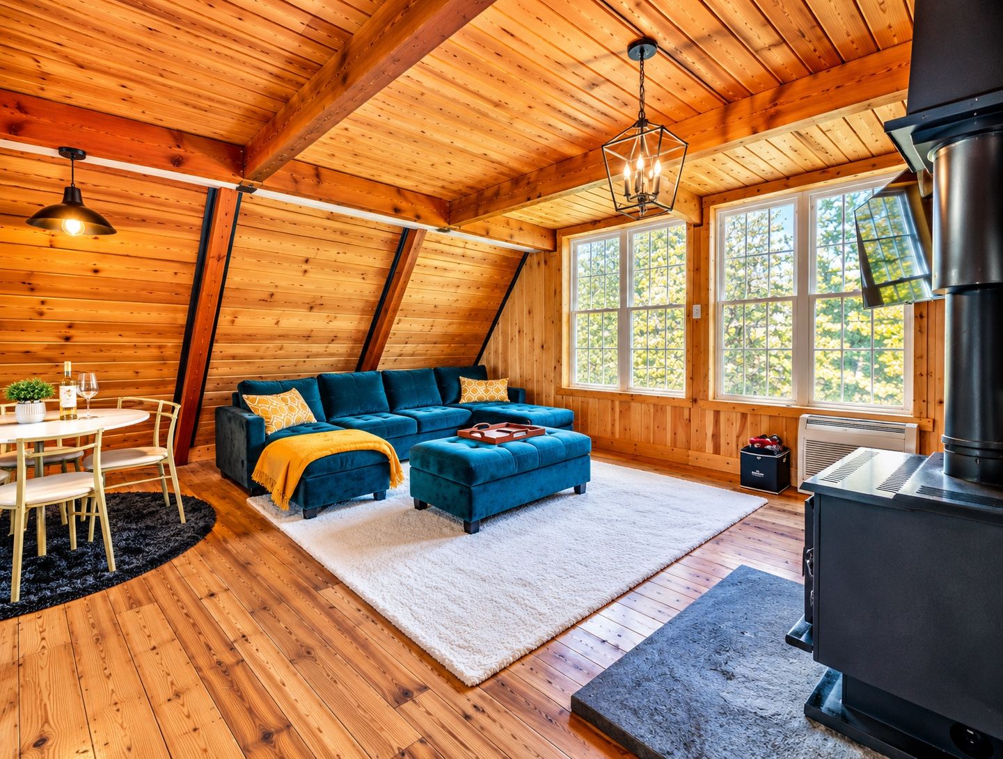 L’intérieur d’un chalet accueillant, avec un plafond en bois, un canapé bleu, une table à manger avec des chaises et une cheminée.