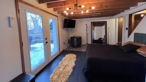 Ein Schlafzimmer mit einem großen Bett, Holzboden, einem Fernseher und Blick ins Freie.