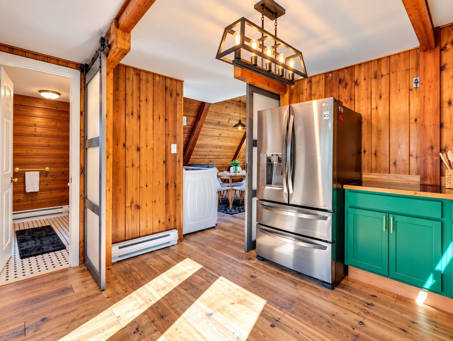 Una cocina con paredes de madera, un refrigerador de acero inoxidable y un armario color aguamarina.