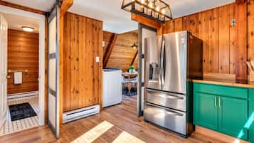 Una cocina con paredes de madera, un refrigerador de acero inoxidable y un armario color aguamarina.