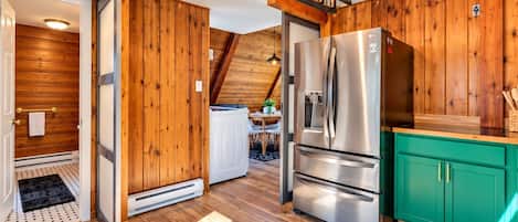 Una cocina con paredes de madera, un refrigerador de acero inoxidable y un armario color aguamarina.