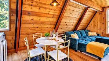 Una habitación acogedora con techo de madera, una mesa de comedor con sillas, un sofá y una ventana.