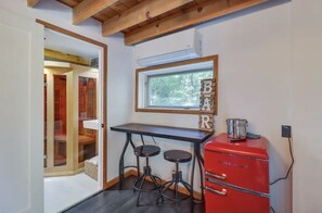 Une cuisine compacte avec un réfrigérateur Galanz rouge, une table en bois et deux tabourets.
