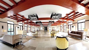 Un hall amplio con techos altos, mobiliario moderno y ventanas grandes.