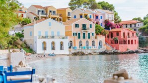 Un hôtel situé sur la côte, avec des bâtiments aux couleurs vives, un mur de pierre et une vue sur la plage.