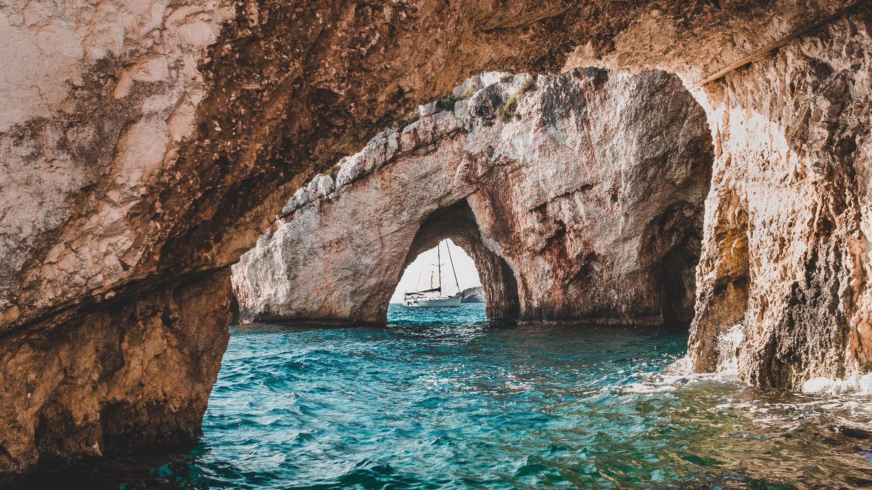 A natural rock formation with an arch over a body of water.