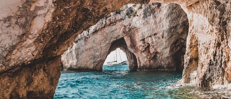A natural rock formation with an arch over a body of water.