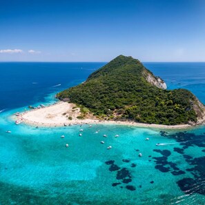 Ein Luftbild einer tropischen Insel mit Strand, klarem türkisblauem Wasser und Booten.