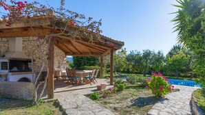 Un bâtiment en pierre doté d’une pergola en bois, d’un espace extérieur aménagé pour s’asseoir et d’une piscine.