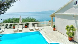 A pool with a view of the sea, white lounge chairs, and potted plants. - Villa Theodora in Nisaki (Corfu)