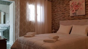 A bedroom with a large bed, a wooden headboard, and a floral painting on the wall. - Villa Theodora in Nisaki (Corfu)