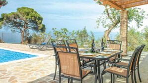 A poolside dining area with a table and chairs, a pergola, and a view of the sea. - Villa Aloni in Koridallos (Zakynthos)