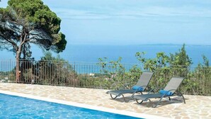 A poolside area with two lounge chairs and a view of the sea. - Villa Aloni in Koridallos (Zakynthos)