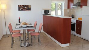 Una cocina compacta con comedor, microondas, cocina y ventana.