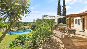 A pool area with a pergola and outdoor seating, surrounded by lush greenery and tall trees. - Villa Irene in Mexilhoeira Grande (Portimão)