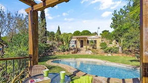 A pool area with a pergola, wicker chairs, and a table with a book and a mug. - Villa Irene in Mexilhoeira Grande (Portimão)