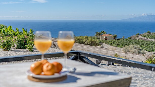 A terrace with a table set for two, overlooking a coastal view. - Cliff Haven Sea View Apartment - Adults Only (Santiago del Teide)