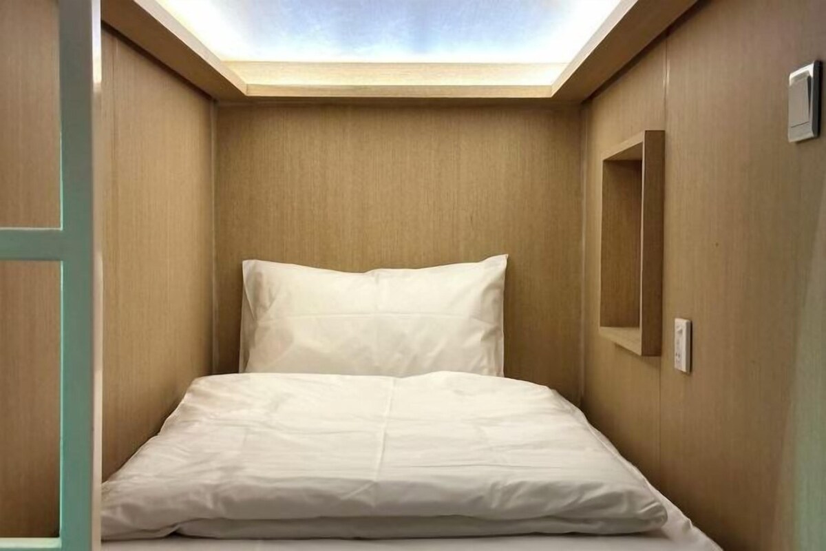 Une petite pièce, de taille modeste, avec une lucarne au-dessus du lit, qui laisse entrer la lumière naturelle.