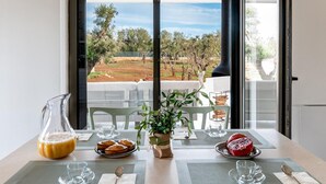 A dining table with a view of the sea, a pitcher of orange juice, a plate of pastries, and a potted plant. - Villa Belkis 6 Emma Villas (Ostuni)