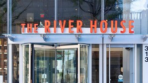 Rakennuksessa on kyltti, jossa lukee ”THE RIVER HOUSE”, ja sen yläpuolella on pyörivä ovi.