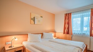 A hotel room with a double bed, bedside tables with lamps, a radiator, and a window with curtains. - Beautiful holiday apartment in Niedernsill (Niedernsill)