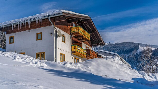 A snow-covered chalet with a wooden balcony and a clear view of the surrounding snowy landscape. - Beautiful holiday apartment in Niedernsill (Niedernsill)