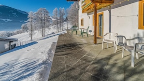A building with a wooden balcony overlooking a snowy landscape with trees and a mountain in the background. - Beautiful holiday apartment in Niedernsill (Niedernsill)