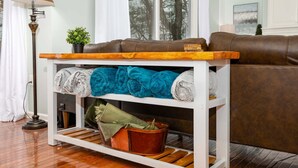 A living room with a brown leather sofa, a wooden coffee table, a white shelf with rolled blankets, and a floor lamp. - On The Rocks! Spacious family-friendly 4BR home w/ bonus room (Basye)