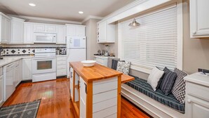 A compact kitchen with white cabinets, a wooden island, a built-in oven, and a seating area with a view. - On The Rocks! Spacious family-friendly 4BR home w/ bonus room (Basye)