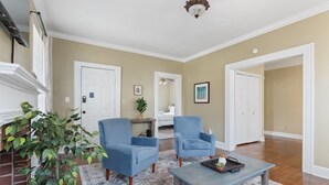 A living room with two blue armchairs, a coffee table, a fireplace, and a large mirror. - Pool & Mins to Zoo - Capitol Heights Hideaway (Montgomery)