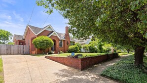 A two-story brick house with a front yard, a driveway, and a wooden fence. - Pool & Mins to Zoo - Capitol Heights Hideaway (Montgomery)