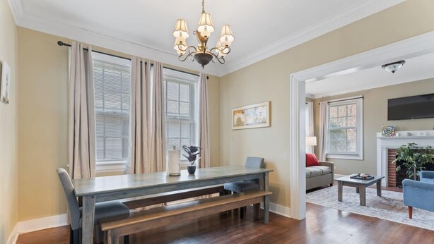 A dining area with a wooden table and benches, a chandelier, and a fireplace in the background. - Pool & Mins to Zoo - Capitol Heights Hideaway (Montgomery)