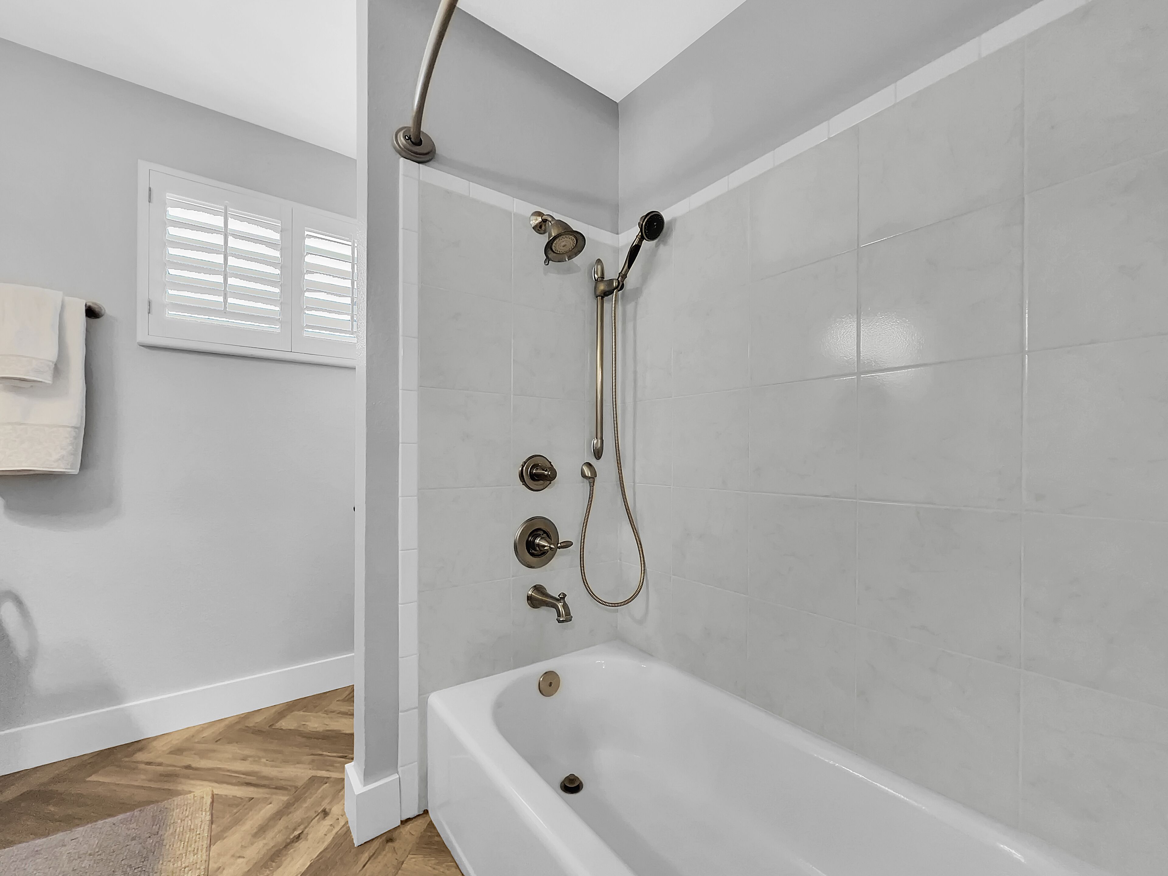 Une salle de bain équipée d’une baignoire, d’une douche avec un pommeau de douche amovible et d’un porte-serviettes.