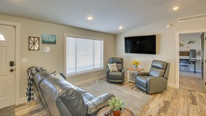 A living room with a leather couch, two armchairs, a flat-screen TV, and a dining area in the background. - Modern Bloomington Home ~ 10 Mi to Bear Lake! (Bloomington)