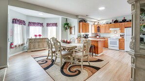A spacious kitchen with wooden cabinets, a central island, and a dining area with a table and chairs.