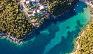 An aerial view of a coastal property with multiple buildings, a clear blue sea, and dense greenery. - Zavia ENA in Syvota With 2 Bedrooms and 3 Bathrooms (Igoumenitsa)