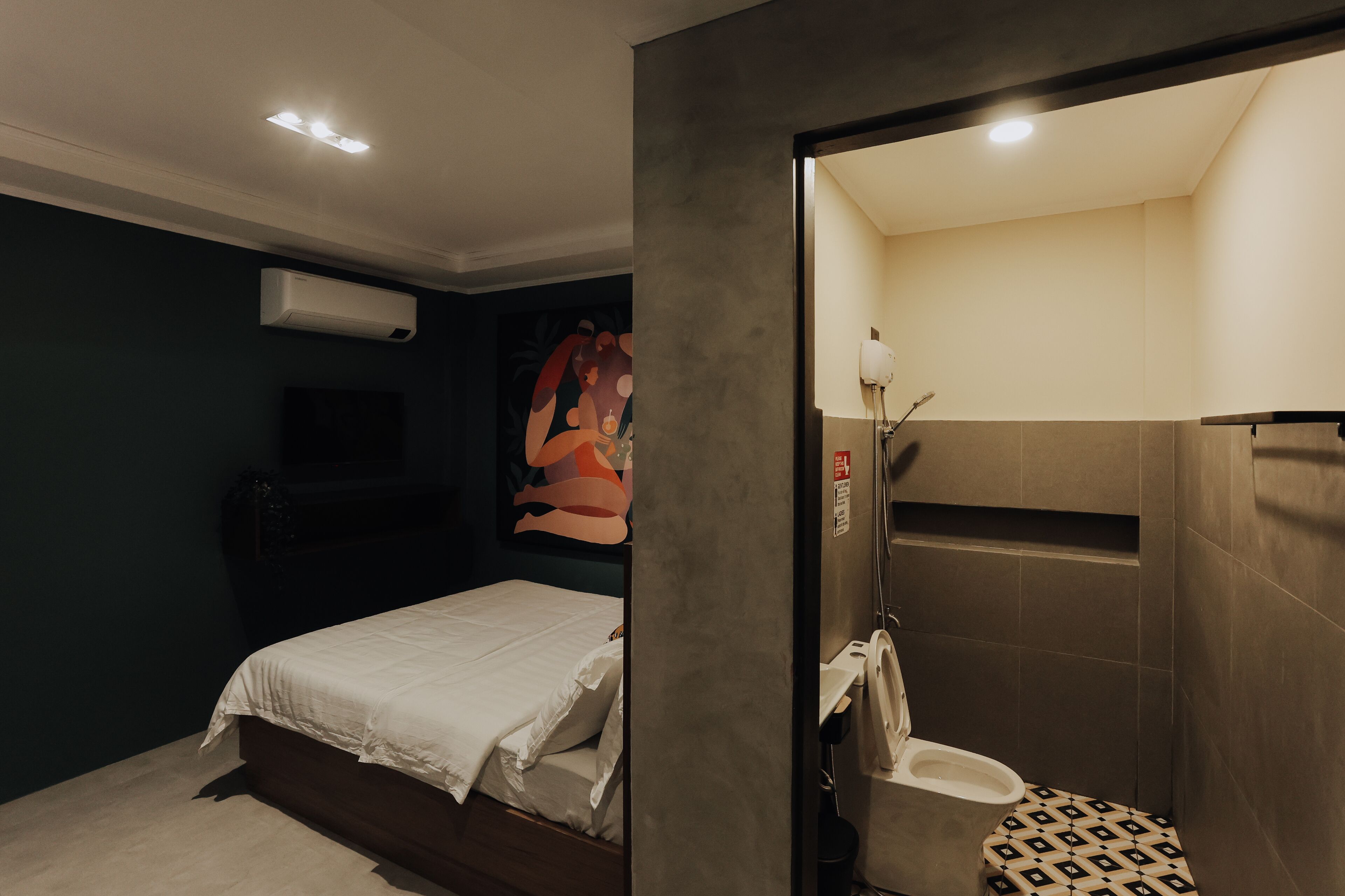 Een slaapkamer met een bed, een nachtkastje en een wandairconditioner.