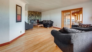 A spacious living room with a stone fireplace, a wooden coffee table, and two dark grey sofas. - 5 Mi to Dtwn Denver: Pet-Friendly Home w/ Patio (Denver)