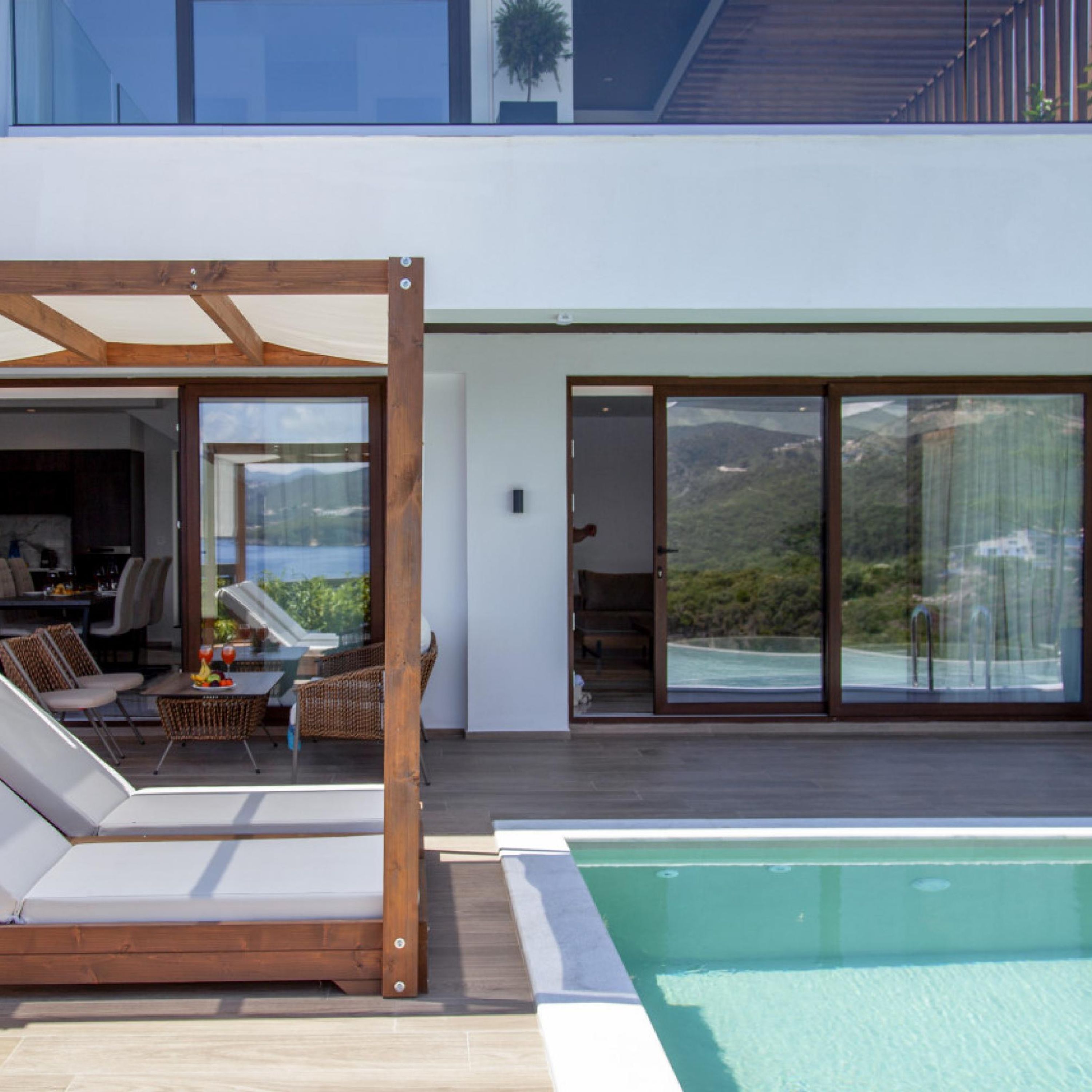Un espace piscine extérieur moderne, doté d’une terrasse en bois, de chaises longues et d’un coin repas.