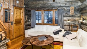 L’intérieur d’un chalet confortable, avec un canapé blanc, une table basse en bois et un tapis aux couleurs vives.