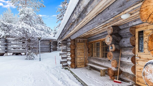 Une cabane en rondins avec une véranda en bois et un banc.