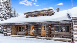Une cabane en rondins dont le toit est recouvert de neige et dont l’extérieur est en bois.