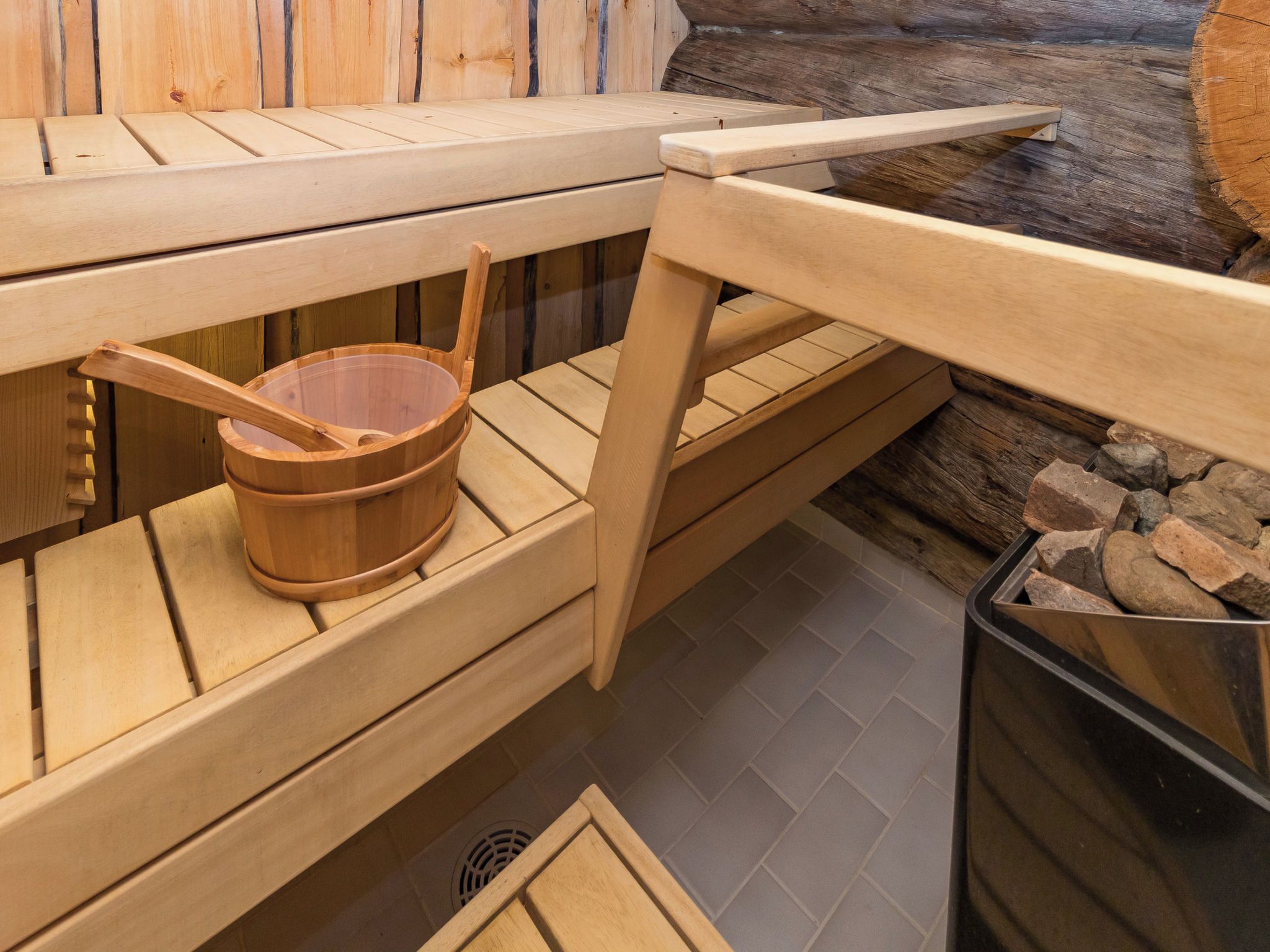 Una sauna con panche di legno e un secchio di legno.