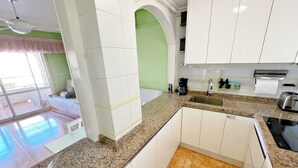 A modern kitchen with white cabinets, granite countertops, and a green accent wall.