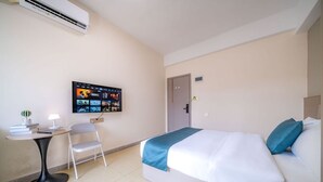 A hotel room with a bed, a desk with a chair, a TV mounted on the wall, and an air conditioning unit. - Moon Hotel Apartment Guangzhou Baijiang (Guangzhou)