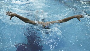A swimmer in a pool with arms extended, water splashing around. - Siliguri Club (Jalpaiguri)