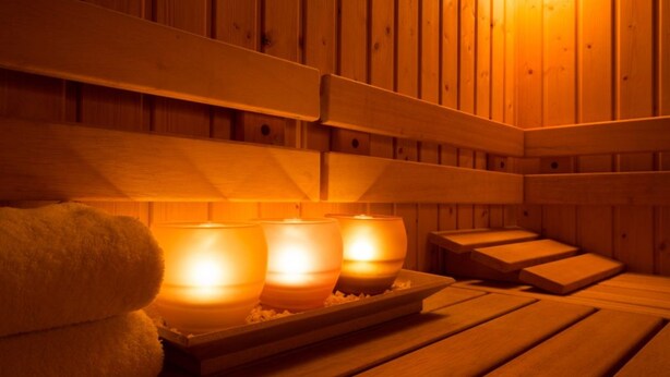A wooden sauna with benches and three lit candles on a tray. - Siliguri Club (Jalpaiguri)
